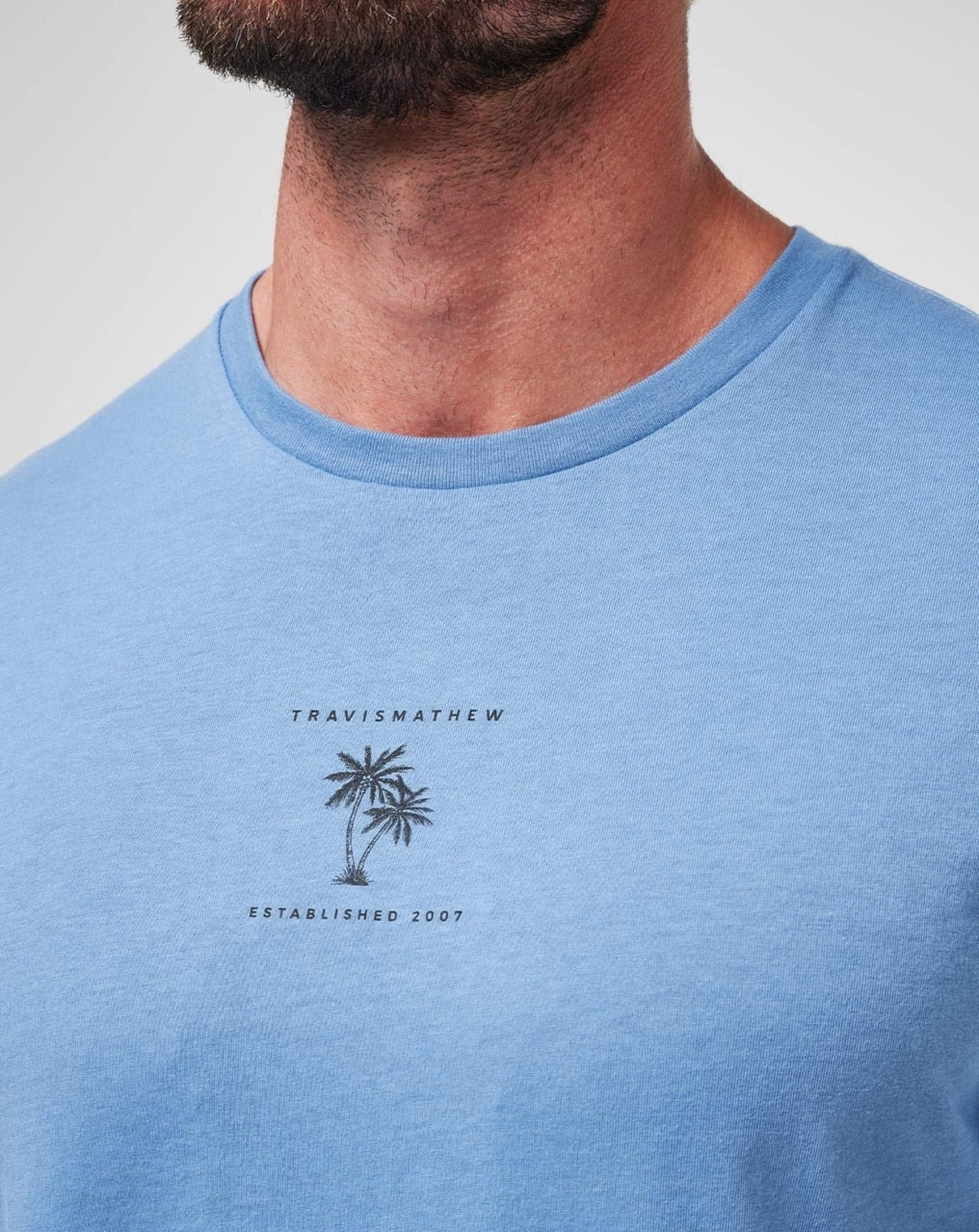 Blue palm tree t-shirt with travismathew branding and established 2007 design.