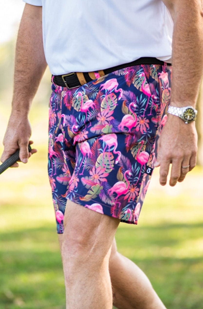 Navy blue tropical print golf shorts with pink flamingos and green leaves, made of stretch fabric.